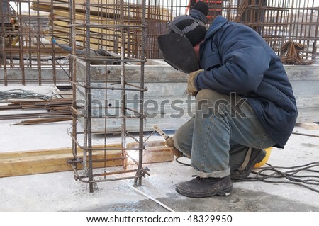 worker welding by electrode a metal lattice reinforcement for concrete pouring