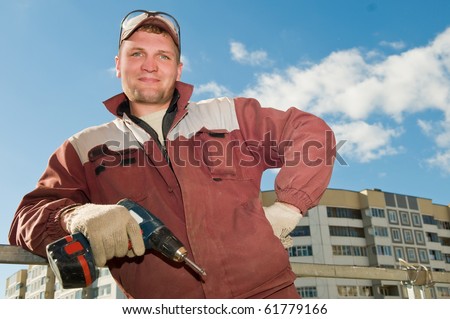 Happy cheerful Builder laborer in work wear with screwdriver machine