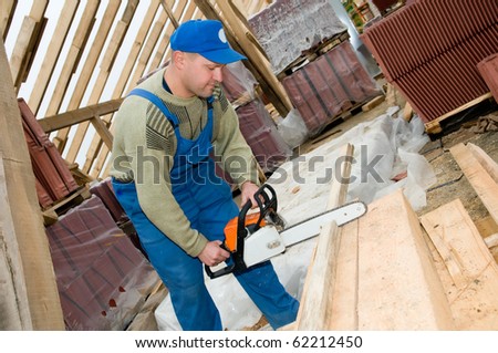 builder worker at roofing works cutting wood timber with po?table saw