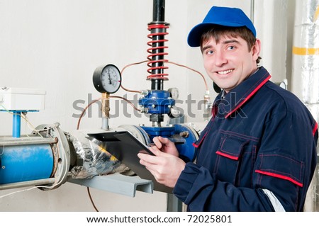 cheerful maintenance engineer checking technical data of heating system equipment in a boiler room