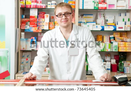 Happy cheerful pharmacist chemist man standing in pharmacy drugstore