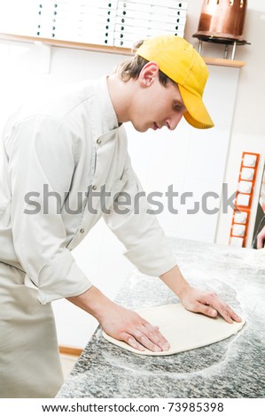 One chef baker in white uniform making bakery dough for pizza at kitchen