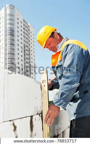 construction mason worker checking quality of bricklaying with measuring level