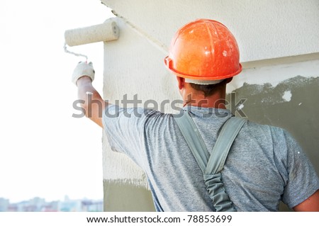 Young painting facade builder worker with roller at thermal insulation works