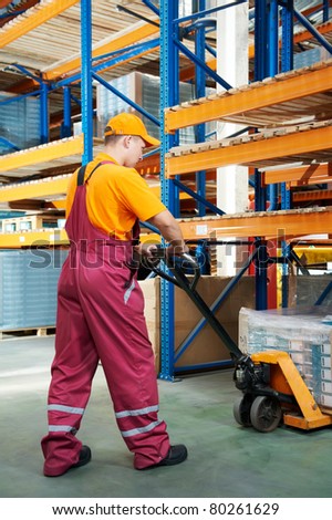 worker with fork pallet truck stacker in warehouse loading furniture panels