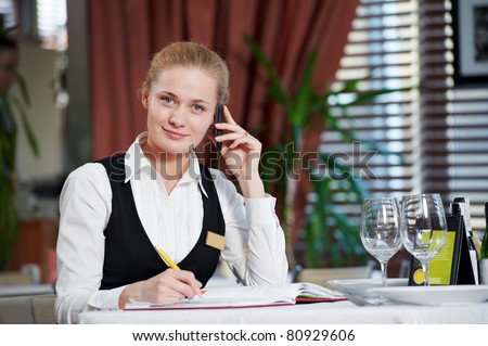 Happy beautiful restaurant manager woman administrator at work place with phone