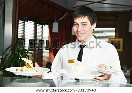 handsome man waiter in uniform with prepared food on plates at restaurant