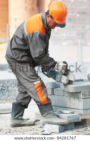 construction worker at curb stone cutting work by cut-off saw with diamond wheel