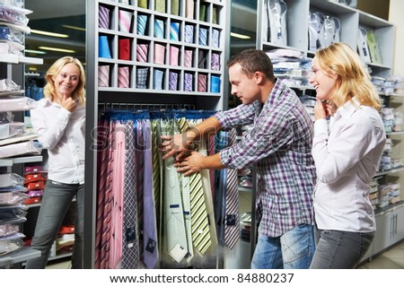 Young couple choosing necktie during clothes shopping at sales store