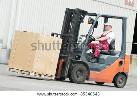 young cheerful warehouse worker driver in uniform driving forklift stacker loader