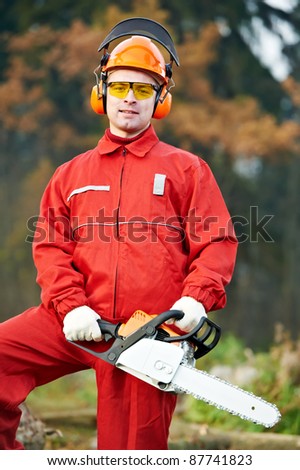 Lumberjack Worker in protective safety work wear With Chainsaw at Forest