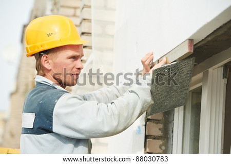 Plasterer facade builder worker with level at thermal insulation works