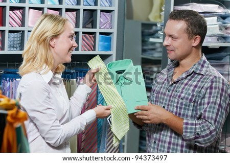 Young couple choosing shirt and necktie during clothes shopping at sales store
