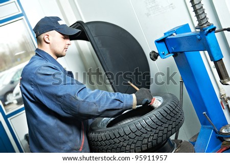 serviceman repairman worker lubricating car tyre at workshop befor fitting