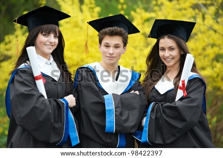 group of three smiling graduate students in spring park after finishing education with diploma