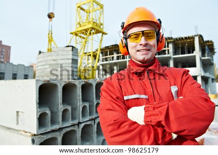 happy builder worker in uniform and safety protective equipment at construction site