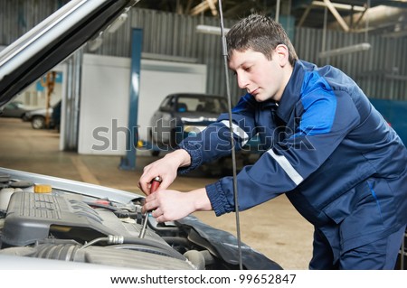 One young auto mechanic tighten screw with spanner during automobile car maintenance at engine repair service station