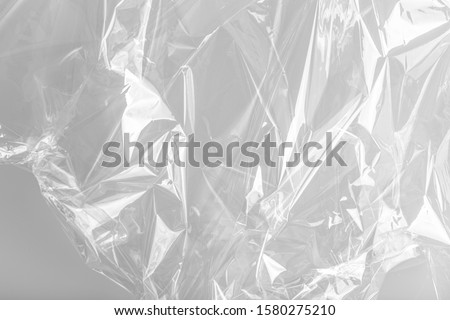 
Close up picture on a plastic transparent cellophane bag on white background. The texture looks blank and shiny. The plastic surface is wrinkly and tattered making abstract pattern.