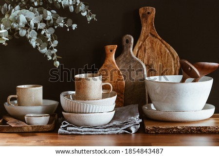 Set of kitchen ceramic tableware and wooden cutting boards on a table. Eco style home still life.