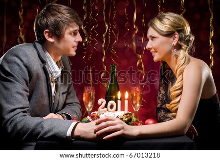 New Year\'s Eve of two beautiful young people with a cake with candles and other Christmas decorations