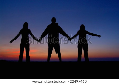 three friends shake hands at sunset
