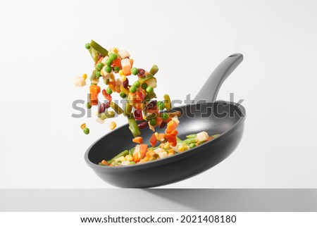 Fresh vegetables fly in a pan on a white background. Cooking with various chopped vegetables in a pan. The concept of healthy eating and diet. 