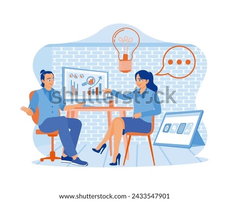 Two business people chatting while sitting behind computers in the office. The excited woman sharing business ideas with a handsome man. A team of people is sitting at desks with laptops. 