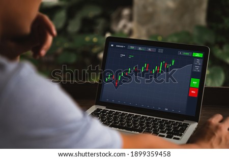 Investment, Shares, online trading and stock market concepts. Asian man sitting looking analyze stocks price on online marketplace on laptop computer before buying investing while working at home