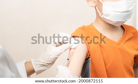 COVID 19 Vaccination for Kids concept. Close up hands of a nurse  giving a little boy first dose of Covid Vaccine in hospital. Authorized, Approved, Trial, Safe, Available, Back to school, Asian, Asia