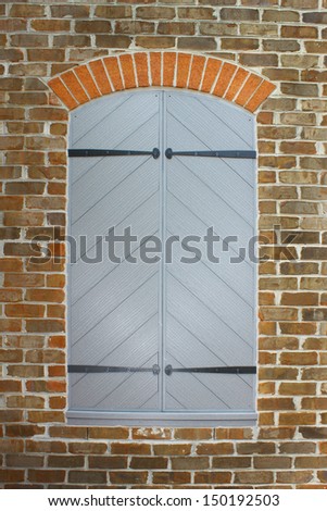An old wooden shuttered up window in the side of an old brick building