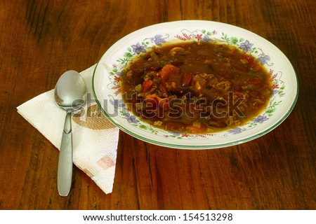 A fresh made bowl of Chili beans also known as chili con carne in a ceramic bowl on a wooden table