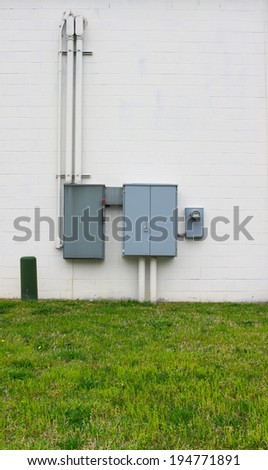 The power supply electrical boxes coming underground from the utility company to the business through the back wall