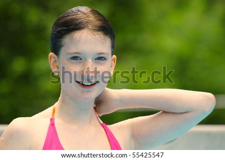a young girl all wet and posing after coming up out of the swimming pool with room for your text