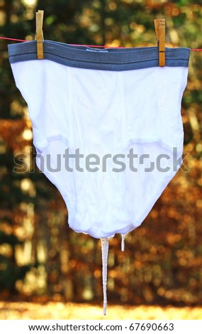 A pair of clean just washed underwear hung outside to dry on a cold winter day with ice cicles hanging off of them using selective focus and a shallow depth of field with room for your text