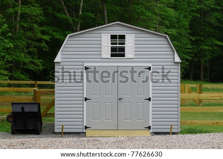 A nice new storage shed outside of a fenced in  back yard with a trailer beside it with room for your text.