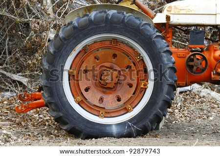 An old farm tractor wheel on an old farm tractor in the woods.