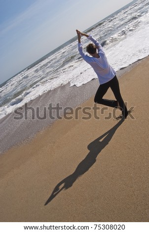 Attractive woman in her 40s doing a yoga tree pose on a secluded beach. Image was taken at the Outer Banks in North Carolina