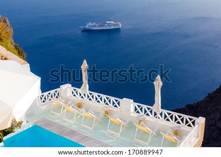 Sunbeds near swimming pool, on top of balcony with great view in Fira village, Santorini, Greece
