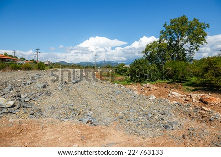 Construction site against a blue sky in Greece with dirt and excavated land in foreground. General construction scene