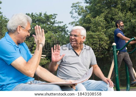 Two happy senior men reading newspaper at park outdoor