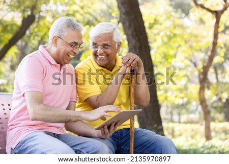 Two senior male friends watching social media content on digital tablet at park
 ストックフォト © 