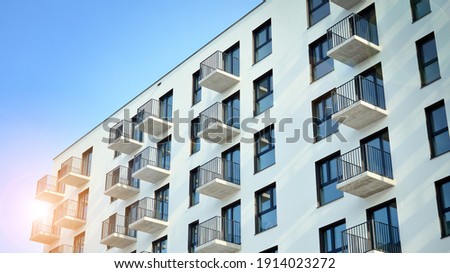 Modern apartment building on a sunny day with a blue sky. Facade of a modern apartment building.Glass surface with sunlight. Rising sun on the horizon.