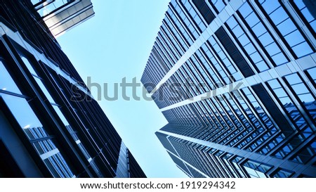 Bottom view of modern skyscrapers in business district against blue sky. Looking up at business buildings in downtown.