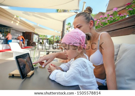 Mother and daughter at beach cafe and looking at the digital tablet screen. Foto stock © 