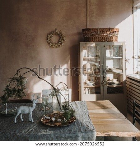 Elegant aesthetic home living or dinning room interior design with dinner table, linen table cloth, fir branch bouquet, Christmas wreath, neutral dusty pink walls. Sunlight shadows on the wall Foto stock © 