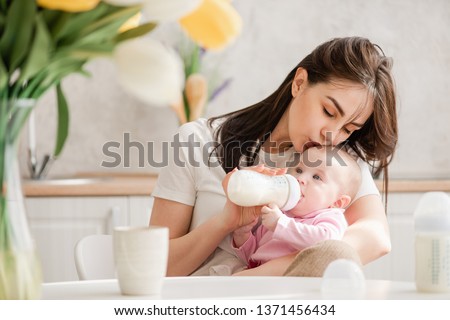 Image, Stock Photo Newborn drinking milk from a baby bottle, sitting on mom legs outdoors