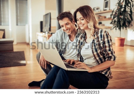 Similar – Foto Bild Ein Paar benutzt einen Laptop, während es zu Hause auf der Couch sitzt.