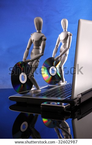 A couple of dummies bring in 2 software CDs to a laptop. Includes first CD label selection path so you can paste into your graphics.