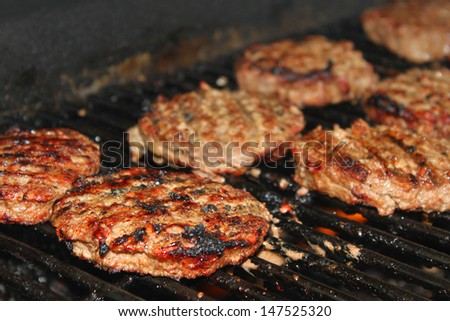 Delicious hamburger patties on a metal grill with fire under