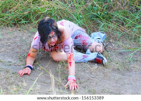 Bloody woman with a ripped shirt wonders in a field